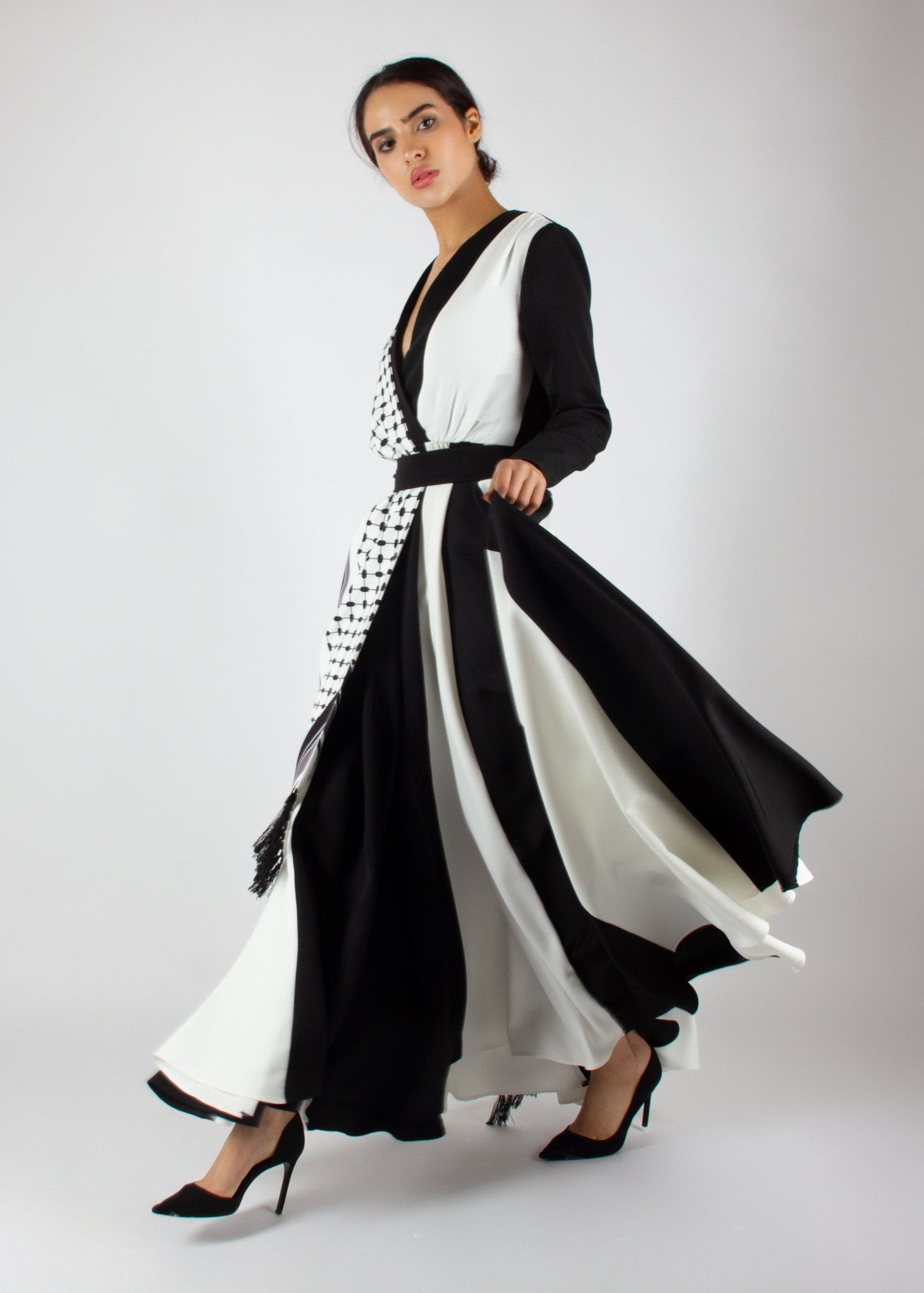 Flowing black and white wrap dress from the HORRA collection by MNour Design, featuring keffiyeh-inspired prints and elegant fringe details. A statement piece blending cultural heritage with modern sophistication. Discover more at www.mnourdesign.com