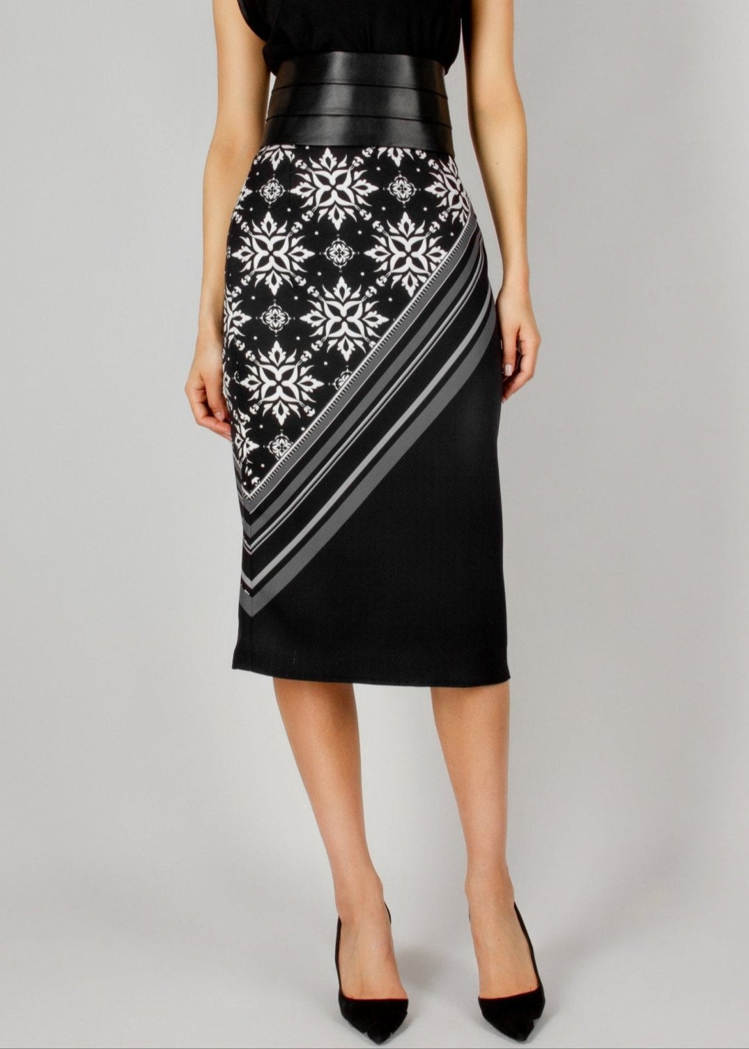 Elegant black midi skirt from the HORRA collection by MNour Design, featuring a bold asymmetrical keffiyeh-inspired pattern. Paired with a sleek black top and a structured leather waist belt for a modern, powerful look. Explore the full collection at www.mnourdesign.com.