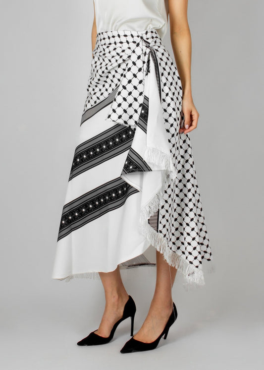 Contemporary white and black asymmetric skirt from the HORRA collection by MNour Design, featuring keffiyeh-inspired patterns and delicate fringe details. Paired with a sleek white sleeveless top for a modern yet culturally rooted look. Explore the collection at www.mnourdesign.com