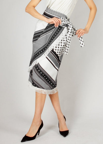 Chic wrap-style midi skirt from the HORRA collection by MNour Design, featuring a striking black-and-white traditional pattern with fringe detailing and a statement side tie. Paired with a sleek satin top and classic heels for an effortlessly elegant look. Explore more at www.mnourdesign.com