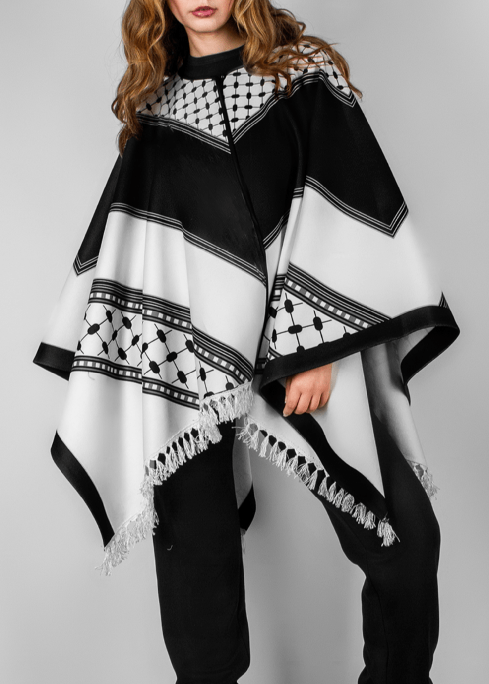 Elegant black and white poncho from the HORRA collection by MNour Design, inspired by traditional Palestinian keffiyeh patterns. Featuring intricate geometric details and delicate fringe edges, this timeless piece blends cultural heritage with modern sophistication. Discover more at www.mnourdesign.com
